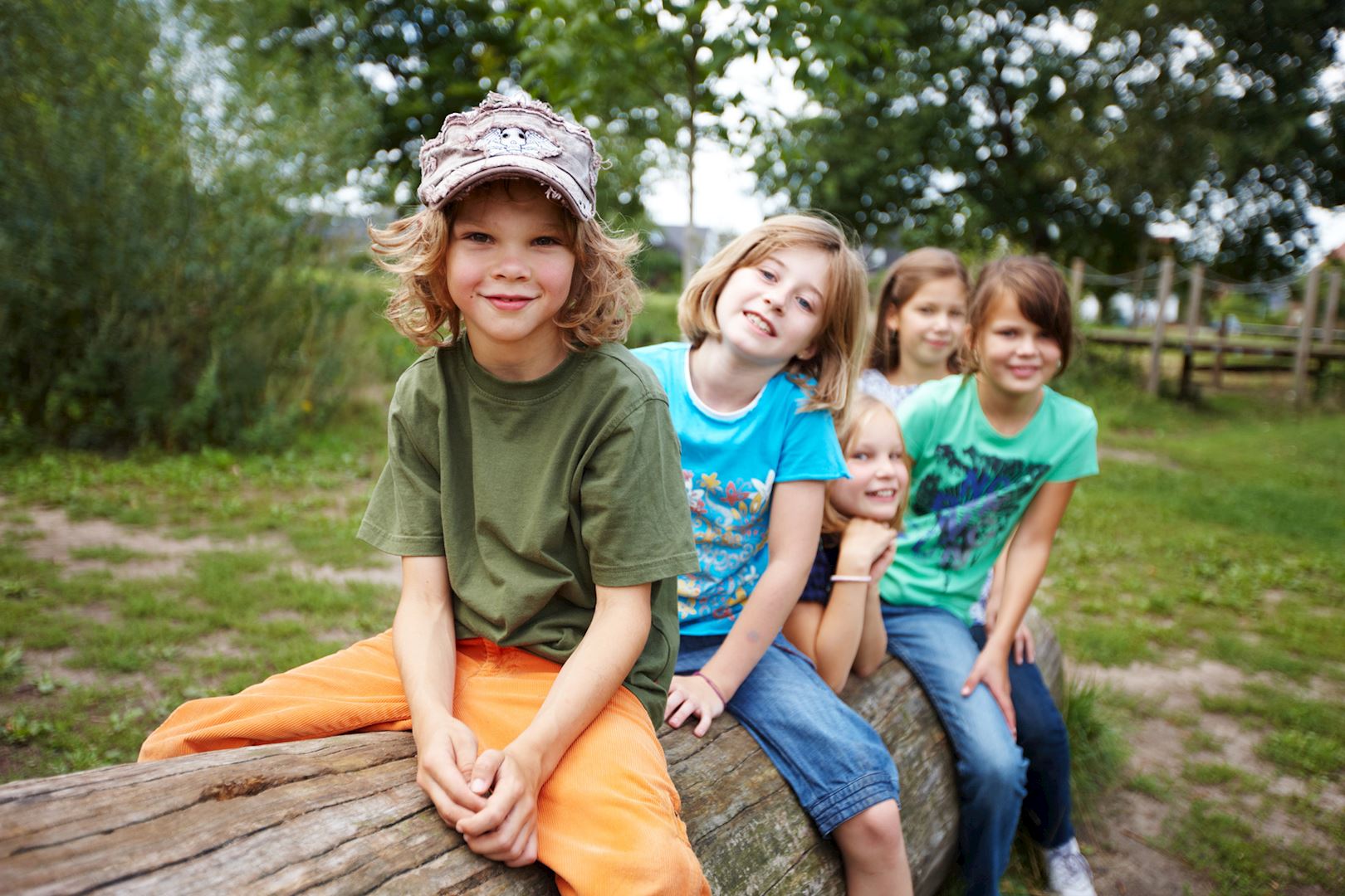 Kinder sitzend auf einem Holzstamm